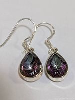 Front view of both earrings showing pear-shaped mystic topaz stones with iridescent purple and green colors in sterling silver bezels and French hooks.