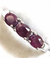 Close-up view of the ring's top showing three oval ruby gemstones set in sterling silver.