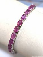 Close-up image showing several oval ruby-colored stones set in sterling silver prong settings on the bracelet.