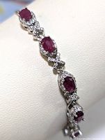 Closeup photo showing the oval ruby stones surrounded by cubic zirconia on sterling silver bracelet.