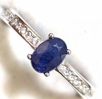 Close-up front view of the ring showing faceted oval blue sapphire and cubic zirconia on band