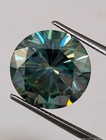 Close-up of round cut moissanite gemstone showing facets and color under light.