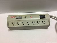 APC PER7 SurgeArrest 7-outlet surge protector, close up showing outlets, LED indicators, and power switch