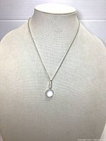 Full view of the necklace on a mannequin displaying the silver-tone chain and round bead pendant.