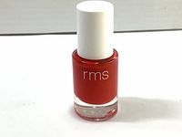 Full view of RMS Beauty nail polish bottle with white cap and red polish inside, showing the front label "rms".