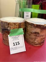 Side view of two round birch bark candles with auction tag in front