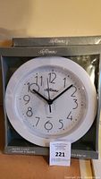 Photo of one Softime quartz wall clock in original packaging showing white clock face with black numbers and hands.
