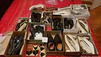 Overview of multiple pairs of black and white ladies dress shoes, presented in shoe boxes, mostly size range 9 to 10