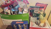 Photo of assorted Christmas holiday items including gift tags, figurines, candle holder, ribbons, towels in a cardboard box