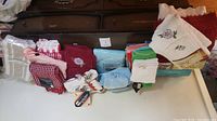 Overview of folded linens, towels, facecloths, tea towels in various colors and patterns with tags
