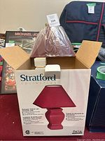 Boxed Stratford Collection lamp with visible box artwork showing red ceramic temple jar design and red shade.