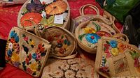 Photo showing seven straw purses accented with colorful floral embroidery, arranged on red fabric.