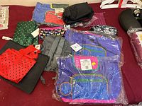 Overview of multiple colorful new utility bags including backpacks, pouches, and reusable bags on a red surface.