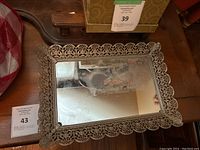 Full view of the rectangular vintage perfume tray with a mirrored base and ornate, decorative metal frame.