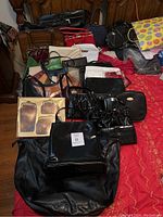Overview of entire lot spread on bed showing over 20 vintage purses and wallets in various sizes and colors.