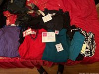 Overview of all women's medium size tops laid out on red surface, showing colors and styles