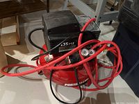 Photo showing red Porter Cable air compressor with black motor housing and red air hose coiled on top.