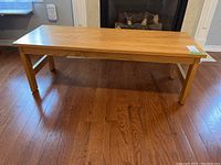 View of the wood coffee table from an angle showing the side and legs on hardwood floor.