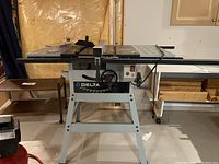 Full view of Delta table saw with metal stand and workspace.