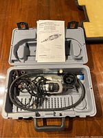 Rotary tool and accessories in gray carrying case with owner's manual on top