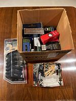 Box filled with multiple sleeves of golf balls and accessories including Castle Bay iron covers and golf tees box