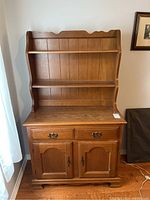 Front view of two piece brown wooden hutch showing drawers, cabinet doors, and shelves.