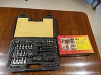 Opened ratchet socket set displayed in black plastic mold case alongside the boxed Arrow Electro-Matic ETF-50 electric staple tool on wood table surface.