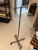 Full view of the adjustable height medical stand with rolling caster wheels and four-leg cross base.