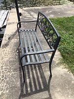 Angle view showing metal slat seating, armrest, and decorative backrest design.