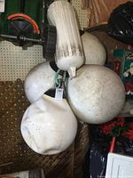 Four large rubber buoys and one large cylindrical boat bumper/fender hanging on a wall