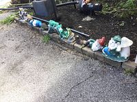 Photo showing the full lineup of garden figures placed on garden stone edging including gnomes, frogs, and a squirrel figure.