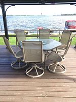 Front view of hexagon table and six swivel chairs on deck overlooking water