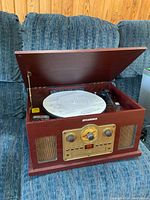 Full view of Sylvania turntable combo unit with lid open showing turntable platter and tonearm inside wooden cabinet.