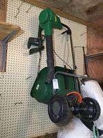 Photo showing green Weedeater electric leaf blower mounted on pegboard with electrical cord and black nozzle