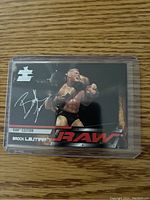 Front of Brock Lesnar rookie card showing him in wrestling action with silver autograph print, RAW branding and protective sleeve.