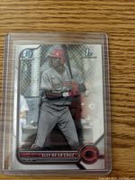 Front of Elly De La Cruz Bowman Chrome rookie card showing player at bat with Reds uniform and logos.