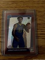 Front of Jonathan Kuminga rookie basketball card showing player in Golden State Warriors uniform with red border and holographic prizm pattern.