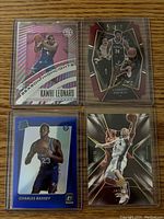 Four NBA basketball numbered cards displayed, including Kawhi Leonard pink prizm, Charles Bassey blue rated rookie, Jason Kidd SPX short print, and Cameron Thomas Select maroon die cut cards.