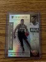 Front of Zion Williamson rookie basketball card with holographic Illusion effect showing player dribbling and portrait.