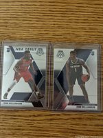 Front view of two Zion Williamson NBA Debut rookie cards side-by-side in protective sleeves on wooden background