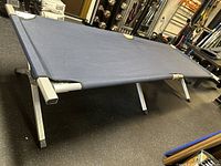 Full view of the adult foldable cot showing navy fabric sleeping surface and metal frame with angled legs