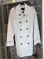 Front view of beige Banana Republic men's trenchcoat, showing the double-breasted button front, collar, shoulder epaulets, and cuff straps.