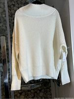 Rear view of off-white chunky knit sweater on hanger showing the knit texture and style