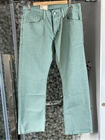 Full front view of light green men's Levi's pants hung for display, showing the fit and cut.