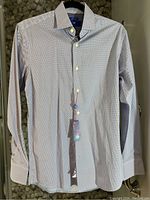 Front view of new men's slim fit shirt with long sleeves, small pattern, button-up style and tags attached.