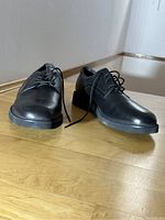 Front angle of black leather dress shoes with laces untied, showing toe and upper leather details