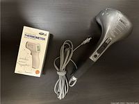 Photo showing the electric handheld massager and medical thermometer box with mascara included in the frame