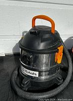 Front view of Kubota shop vacuum showing metal body, orange handle, and attached black flexible hose.