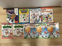 Front view of eight educational books laid out, including math and English workbooks spanning grades 1 to 6.