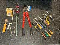 Overview of the full set of tools displayed on a black surface including bolt cutter, screwdrivers, hex keys, and measuring tape